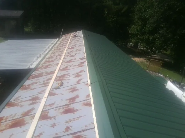 Old rusted panels beside newly installed green metal roofing — Wind Damage Roof Repair by Roofing Brothers in Palmyra